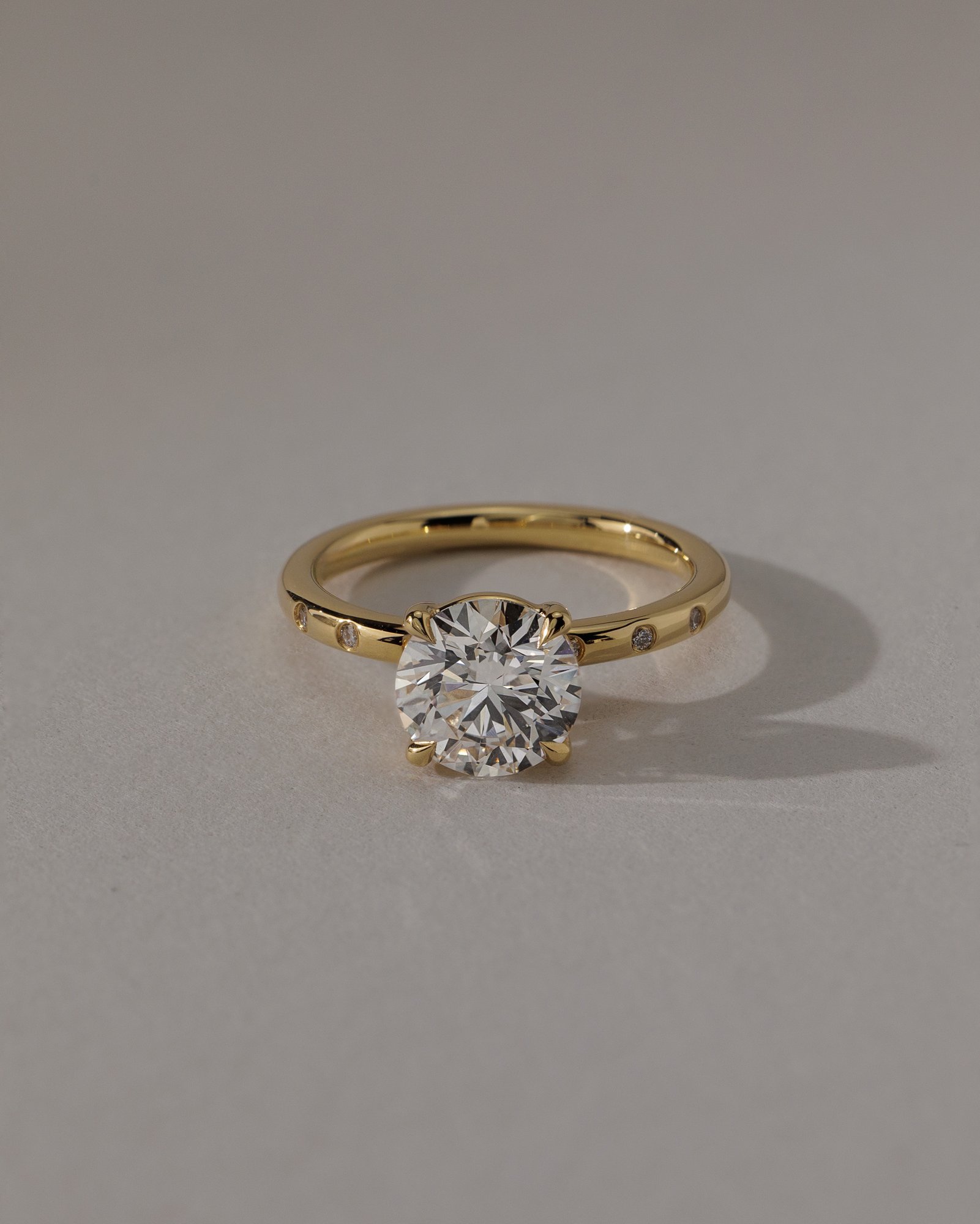 Nekija - 4 Claw Round Solitaire with Accent Stones Lifestyle Image